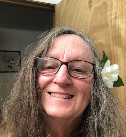 Woman smiling, long hair with flower behind her ear